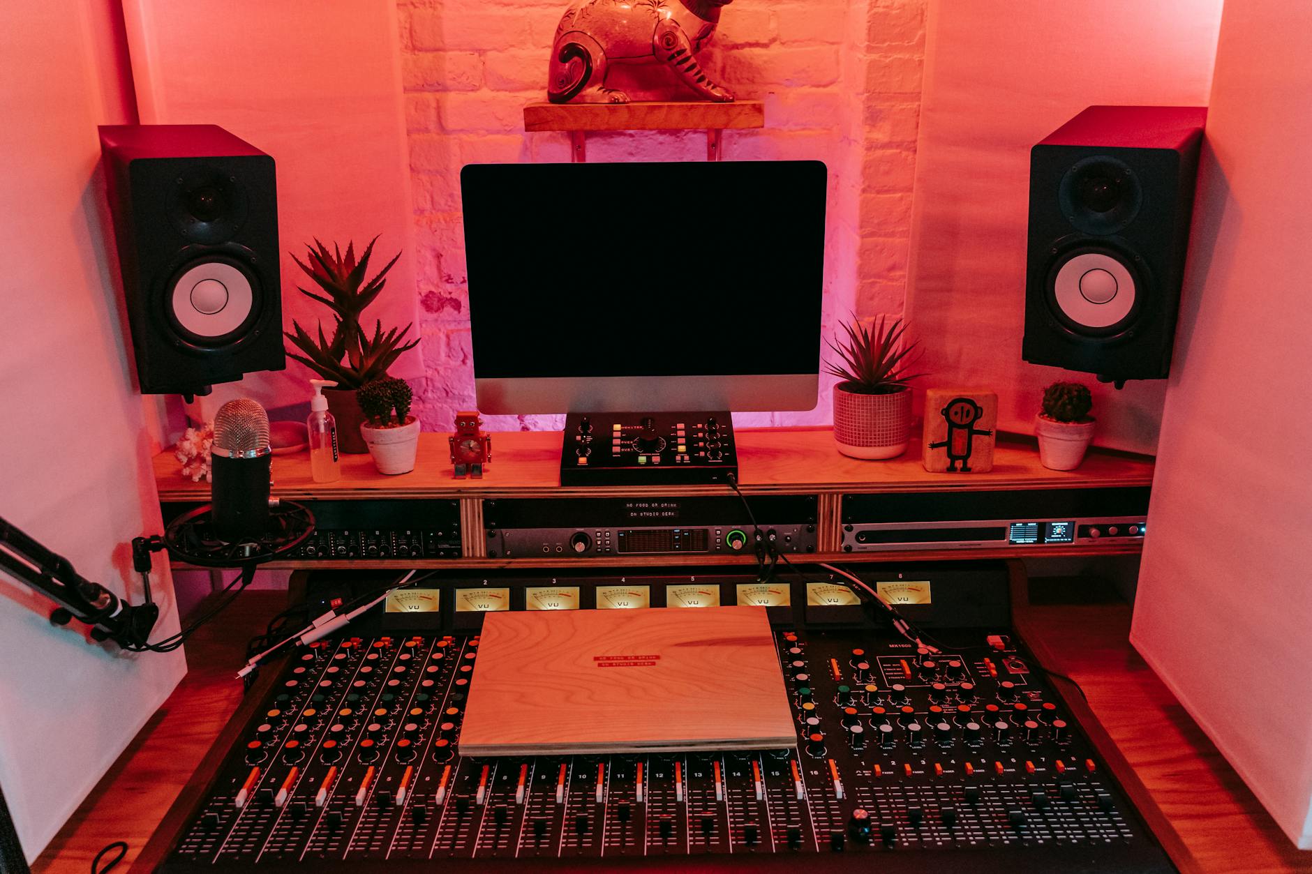 A vibrant music production studio showcasing a mixing console, speakers, and computer display.