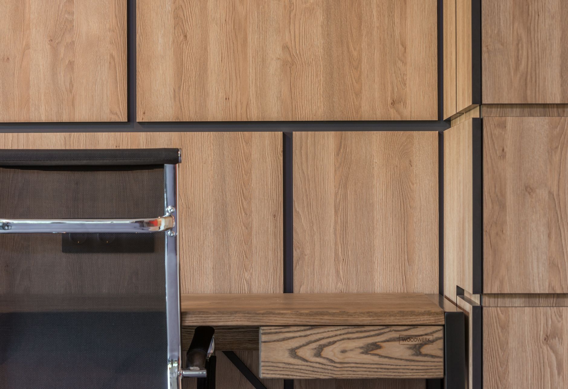Comfortable chair placed at desk near large wooden cabinet in working room of modern apartment