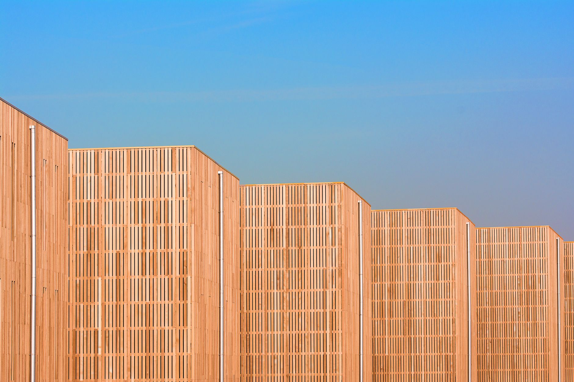 Architectural detail of modern wooden facades with a blue sky backdrop, showcasing unique design and patterns.