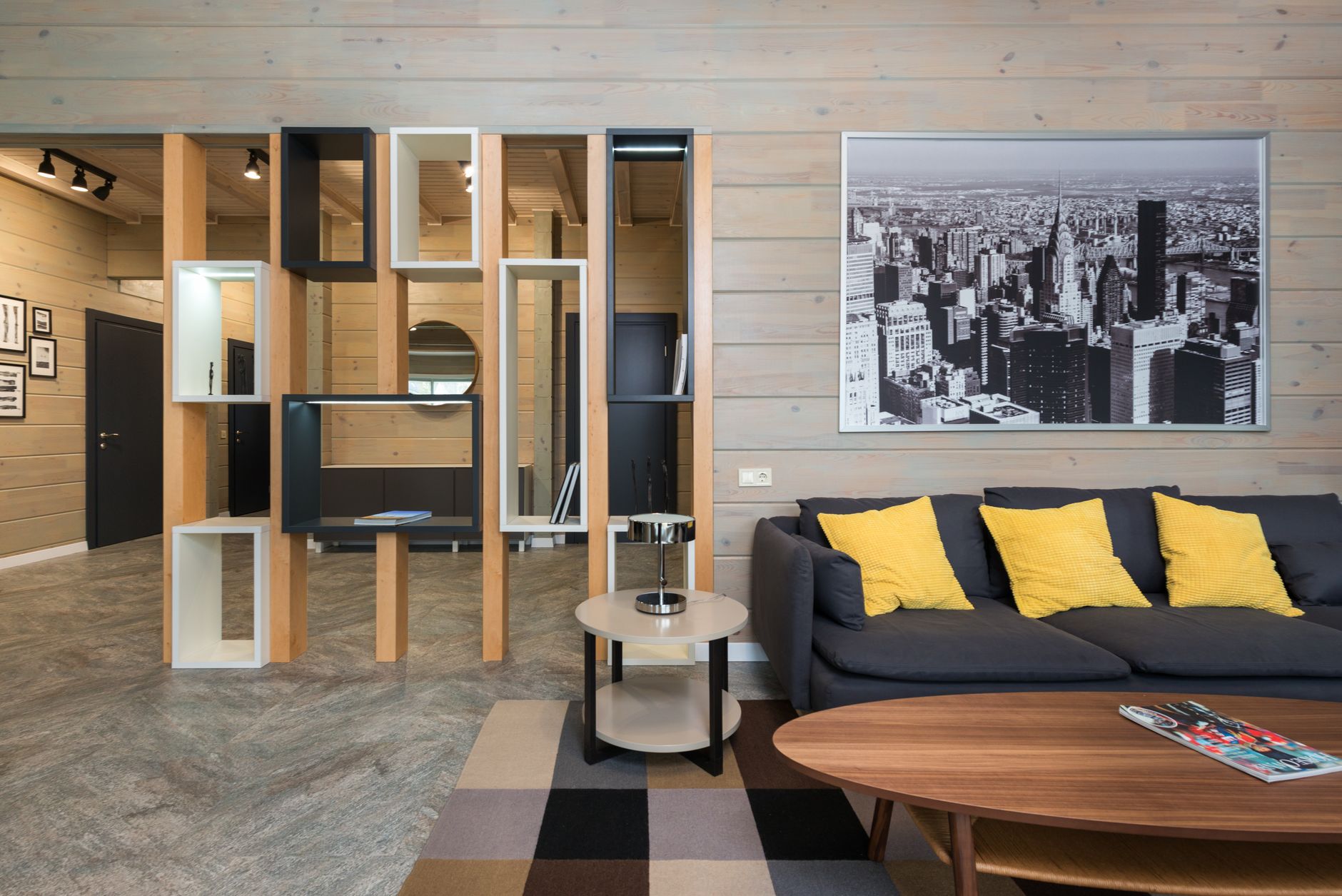 Modern apartment with sofa placed near round table with stylish geometric shelves separating living room from corridor
