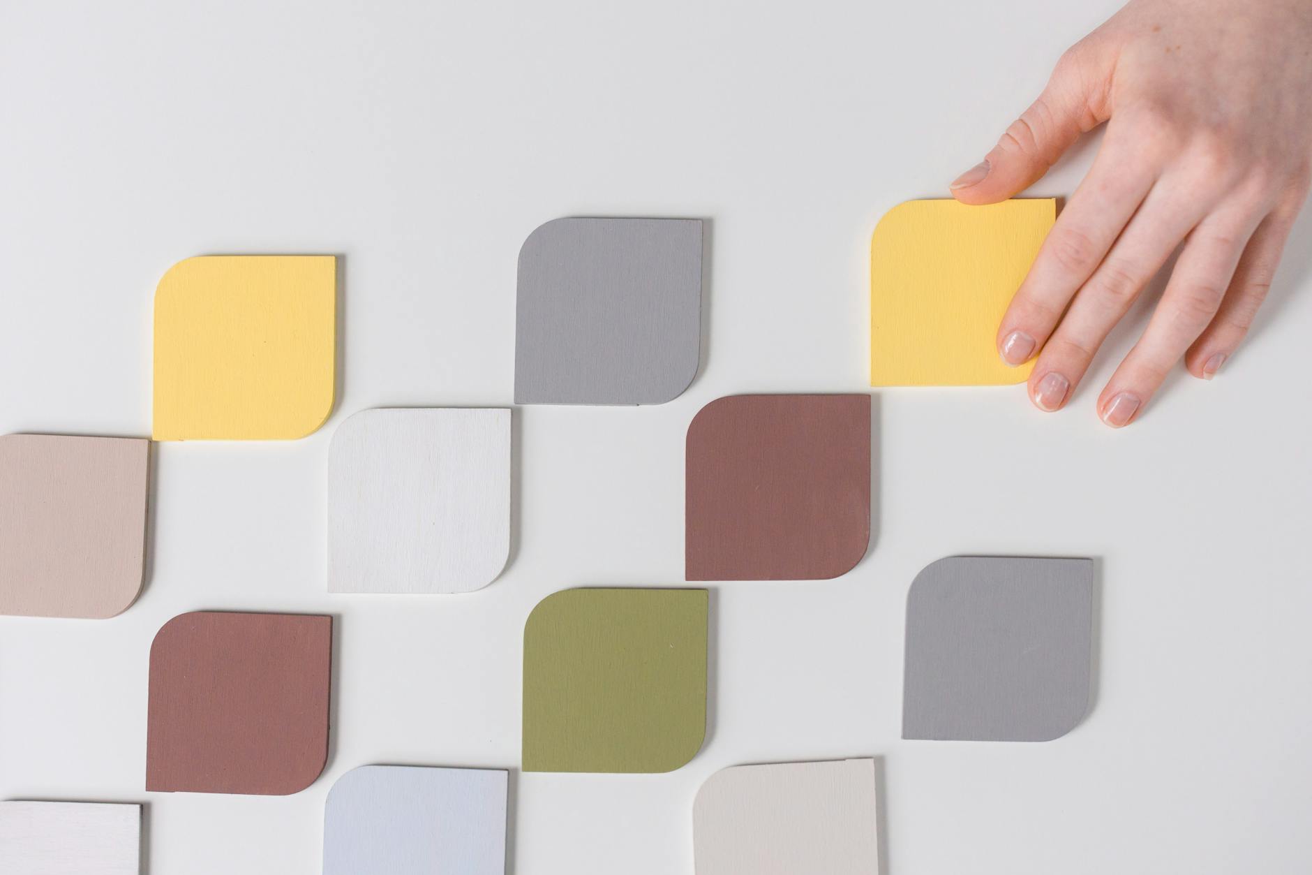 Hand arranging colorful swatches on a white table with a modern minimalist feel.