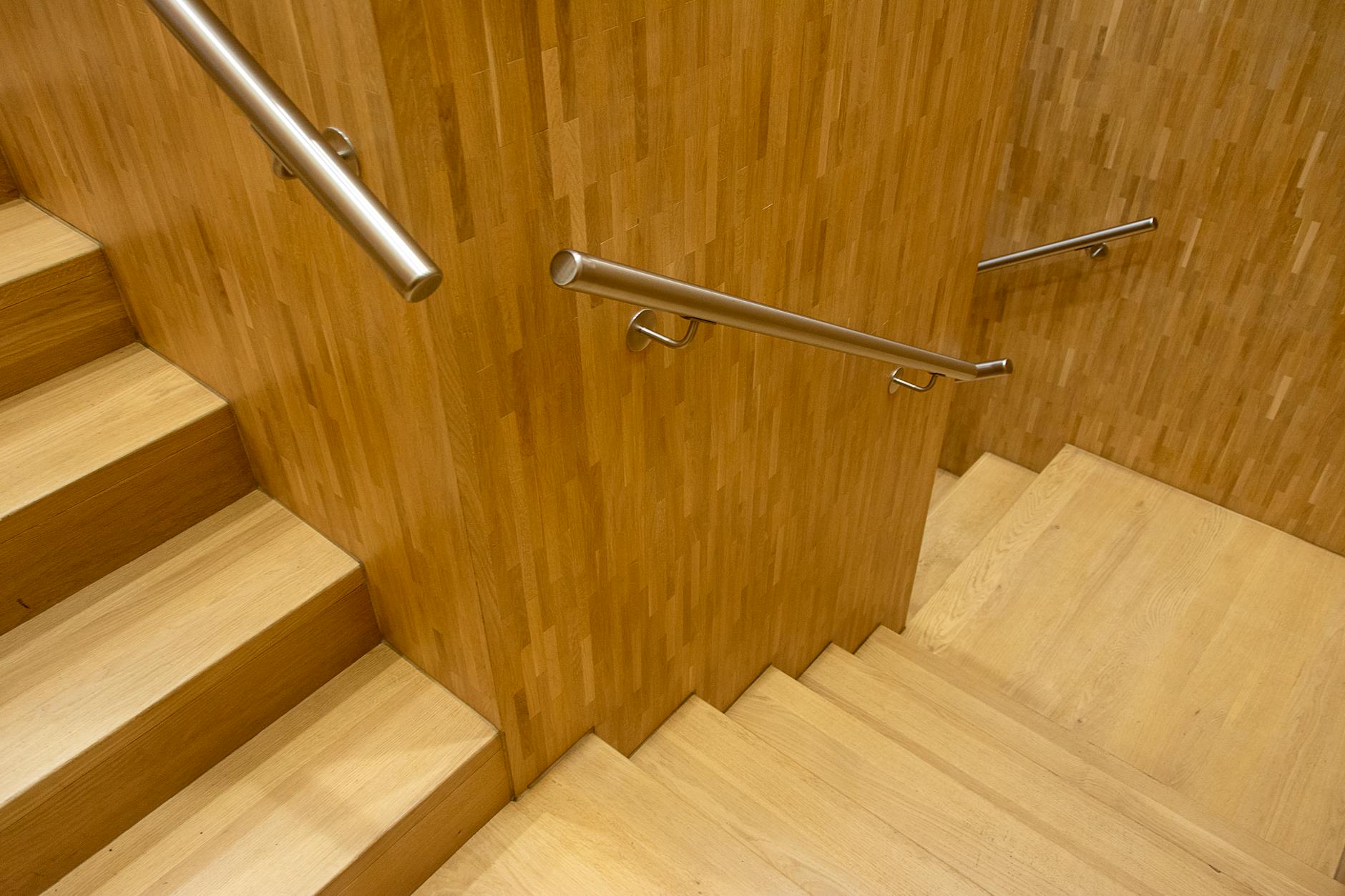 Contemporary wooden staircase with sleek metal handrails in an indoor setting.