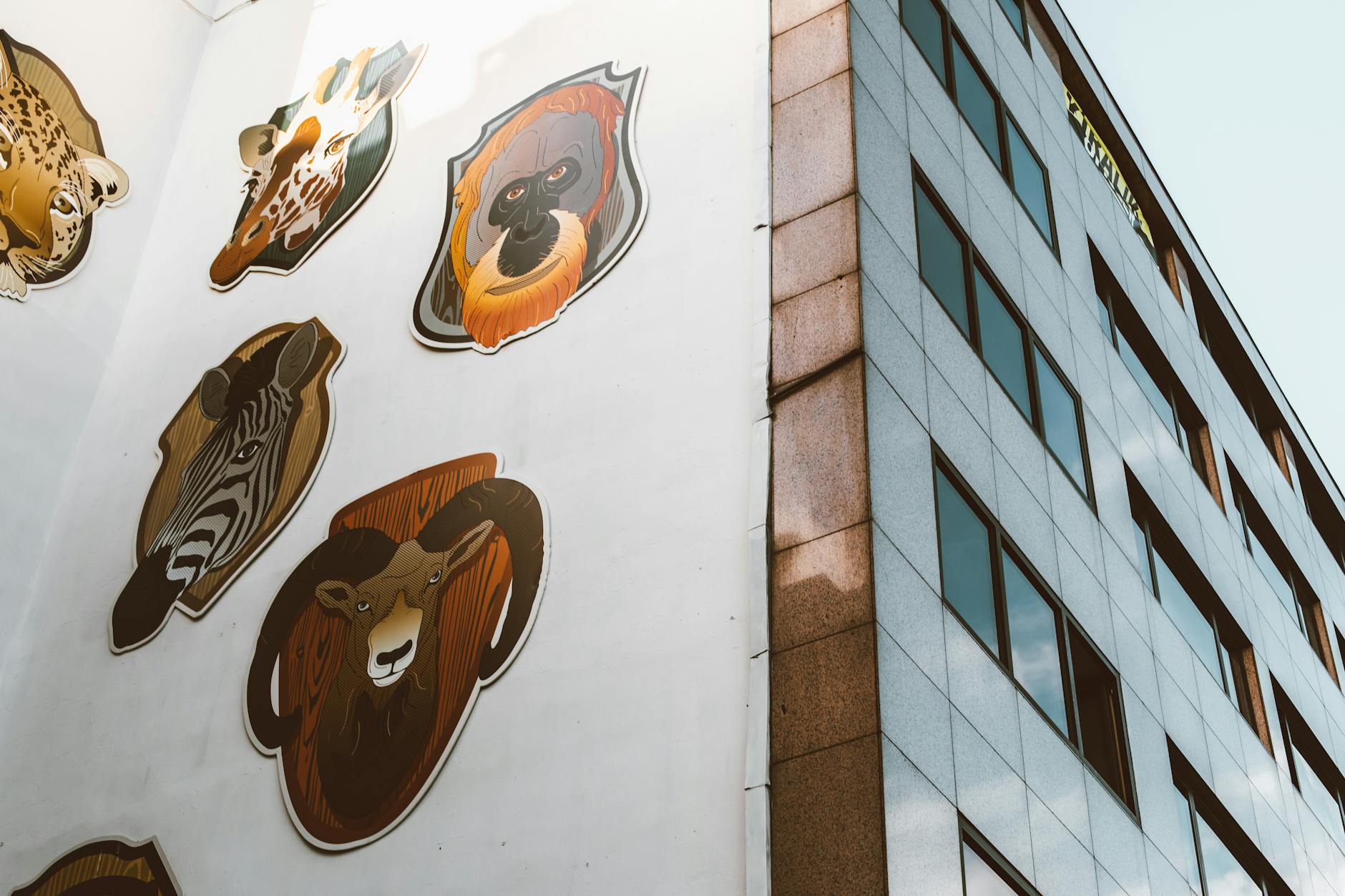 Creative animal mural displayed on the side of a city skyscraper, featuring diverse wildlife.
