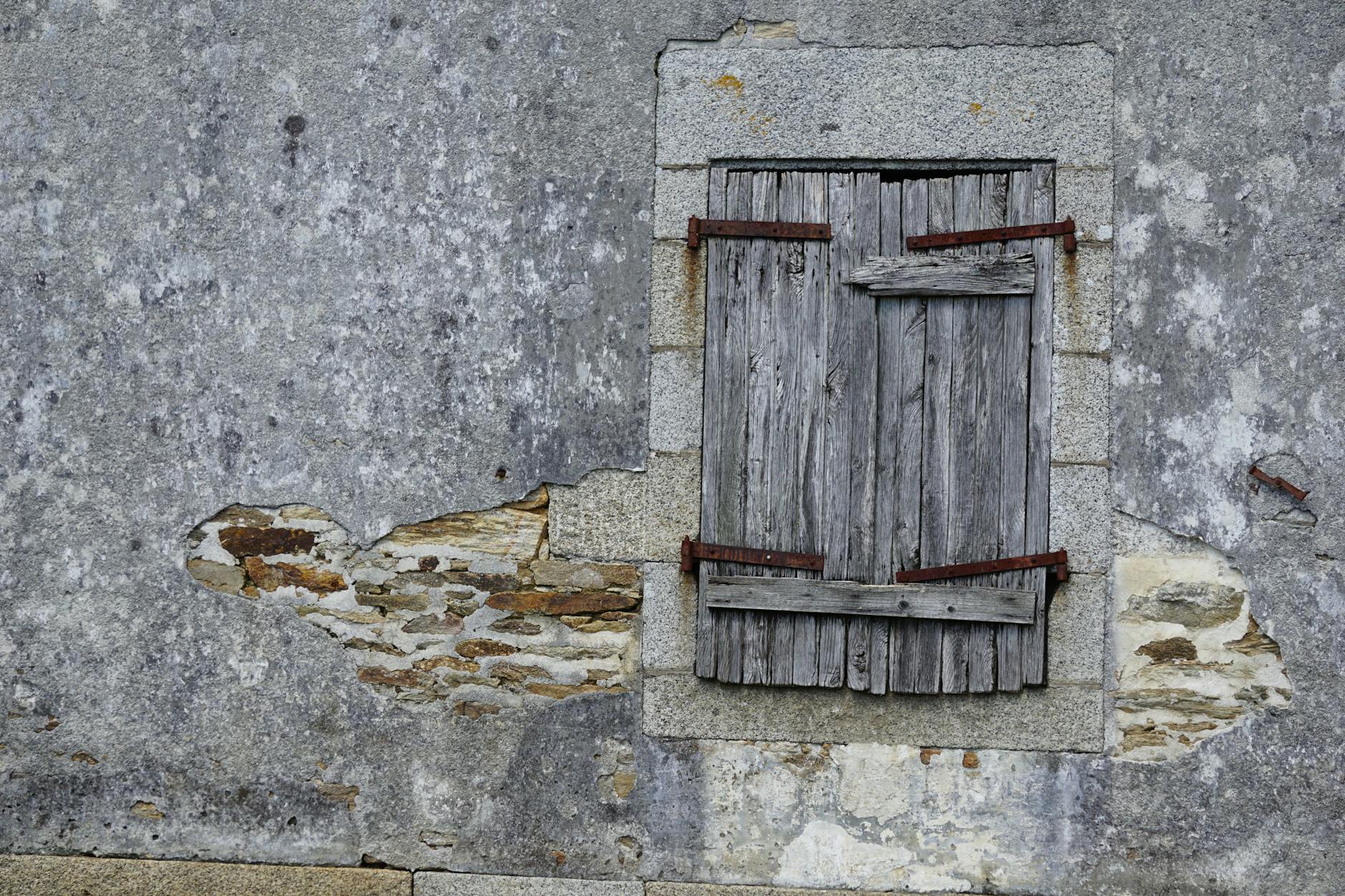 Rustic wooden window on an ancient stone wall captures historic decay and rustic charm.