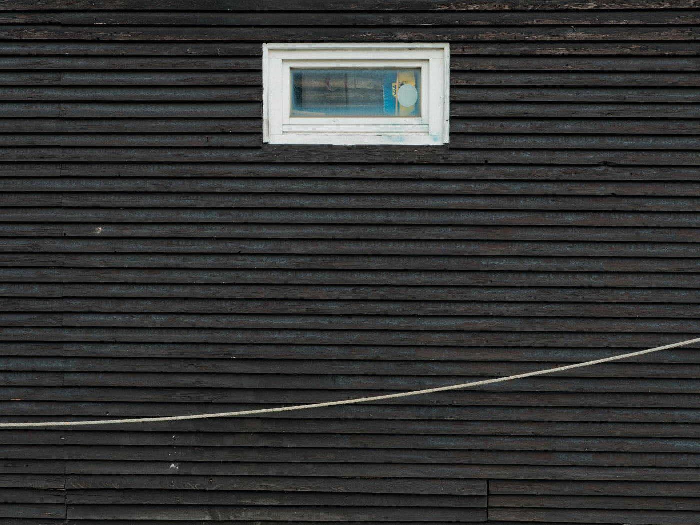 Dark wooden wall featuring a single rectangular window in a minimalist architectural style.