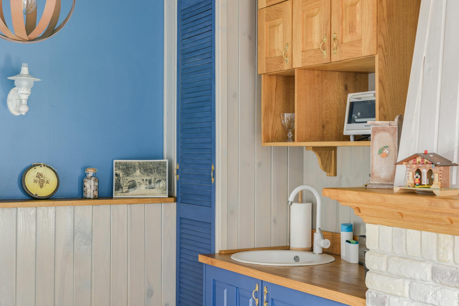 Charming kitchenette with blue and wooden accents, featuring a sink and decorative items.