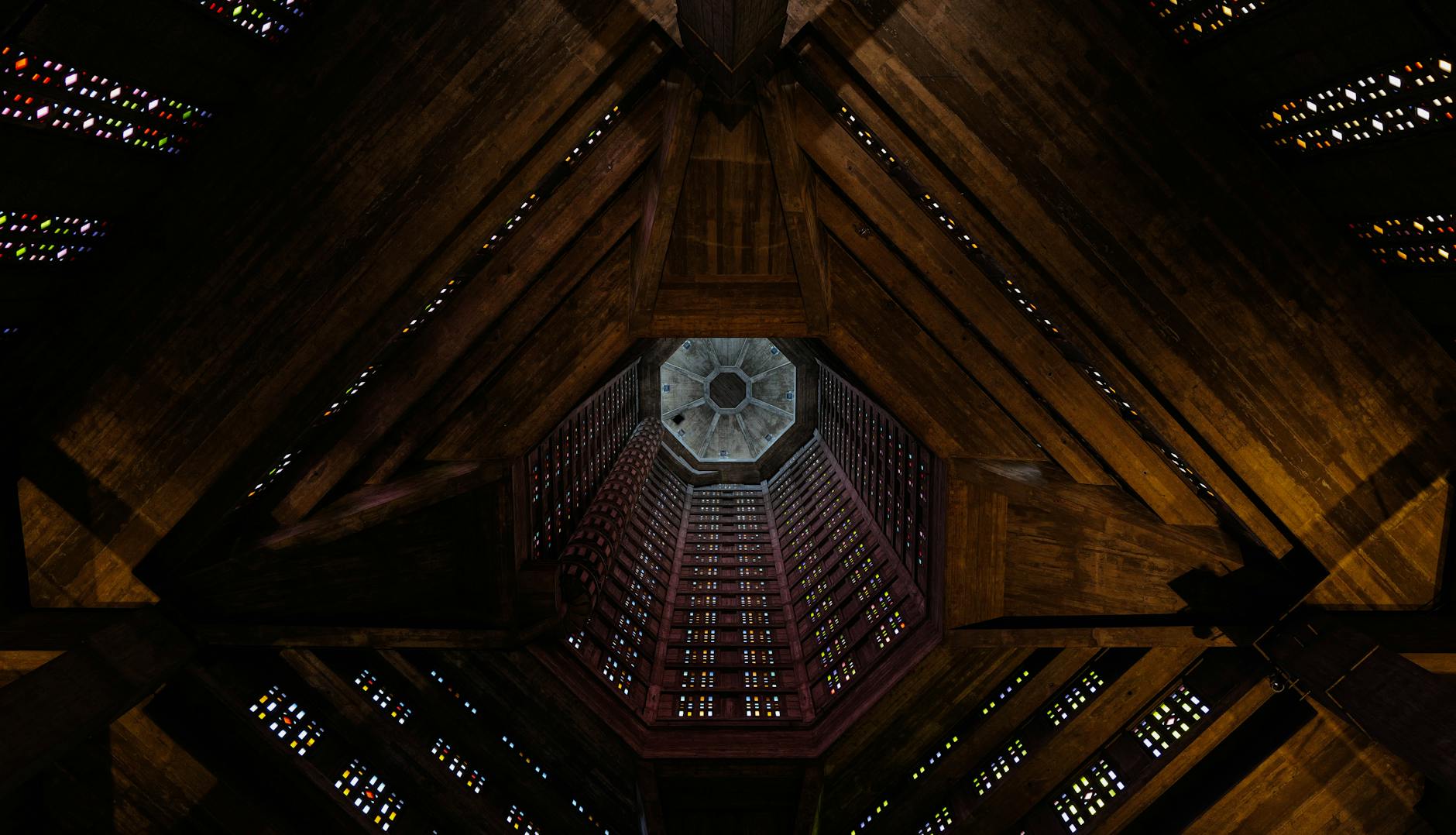 A dramatic view of a hexagonal ceiling with colorful stained glass effects, intricate architectural details.