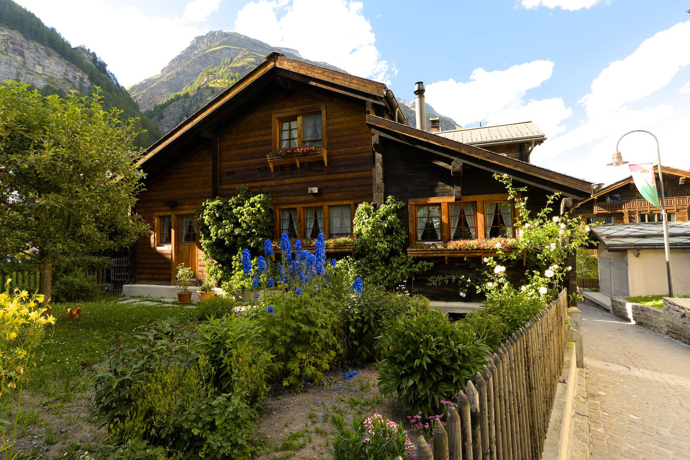 Cozy wooden chalet surrounded by lush garden in picturesque Zermatt under clear skies.