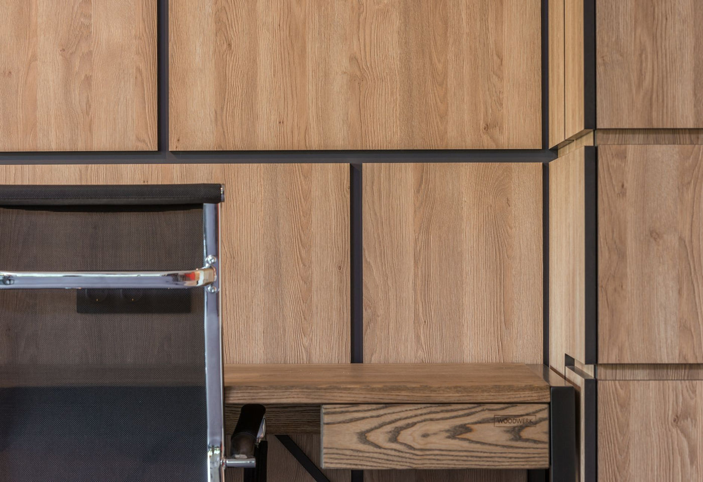 Comfortable chair placed at desk near large wooden cabinet in working room of modern apartment