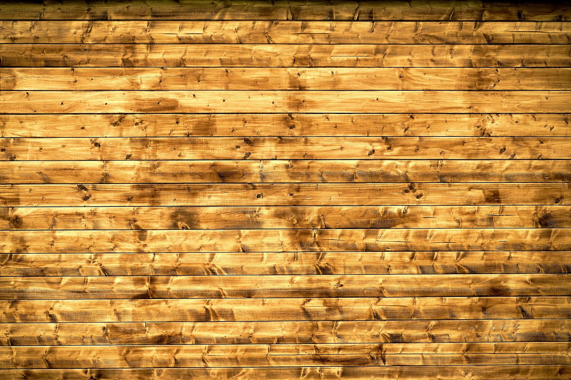 Textured wooden planks forming a rustic wall, perfect for backgrounds or design elements.