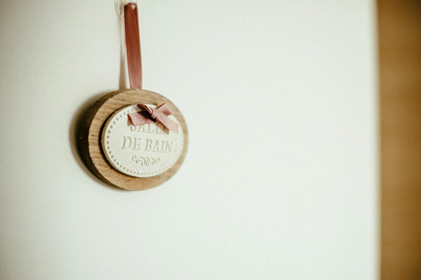 Elegant wooden wall plaque with 'Salle de Bain' text, featuring a pink ribbon, ideal for modern bathroom decor.