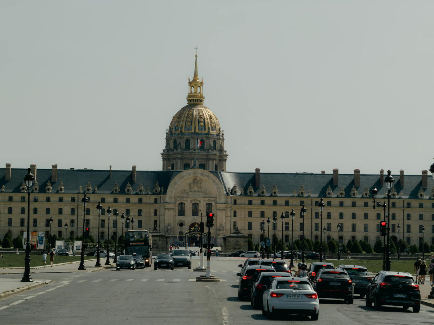 Les Invalides in Paris with city traffic in the foreground under a clear sky.