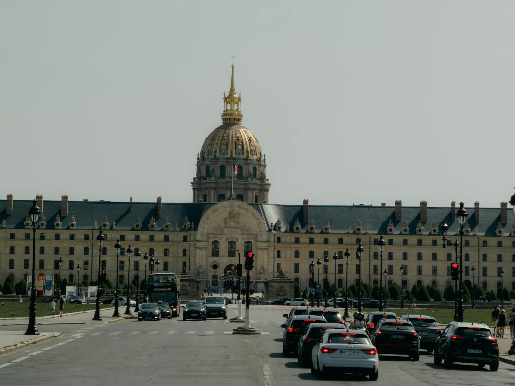 Les Invalides in Paris with city traffic in the foreground under a clear sky.