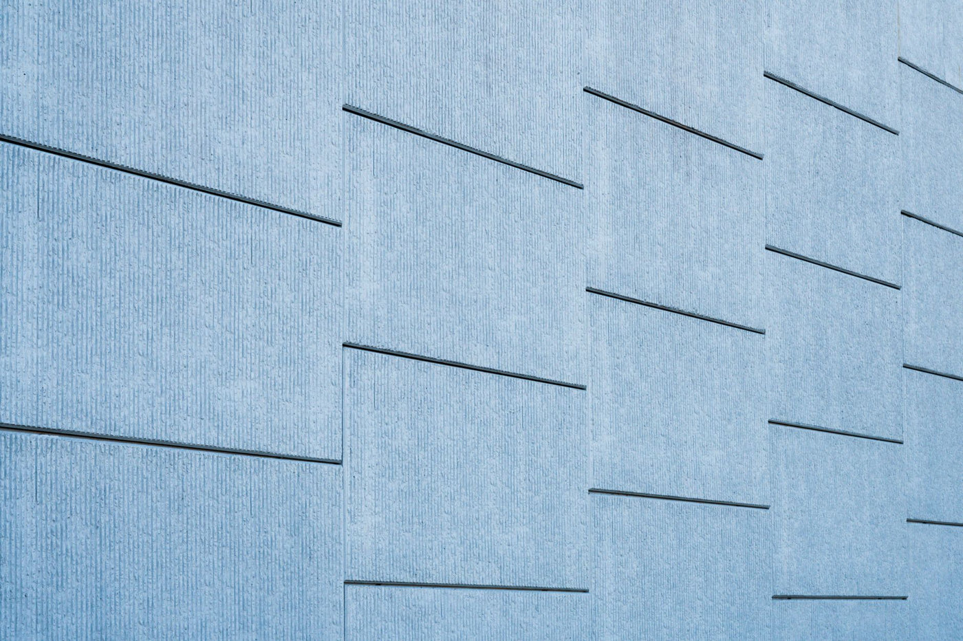 Blue tinted concrete wall featuring sleek geometric lines and modern architecture.