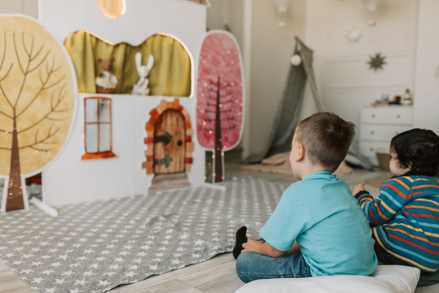 Two children watching a charming indoor puppet show with colorful backdrop.