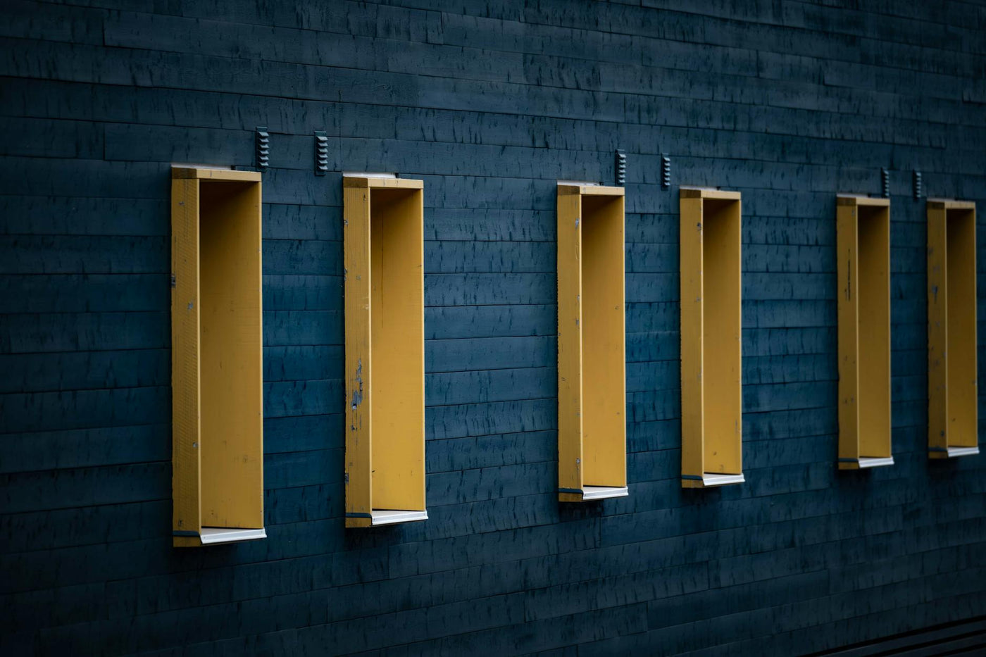 Abstract view of a modern building with repeating yellow structures on a blue wall.