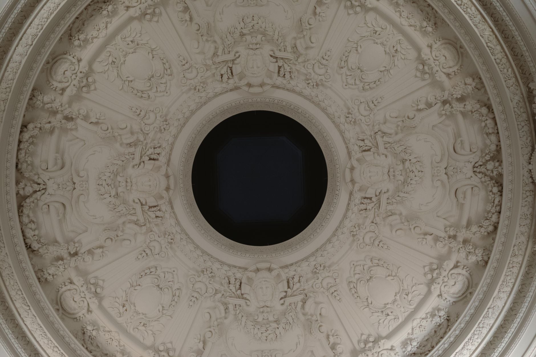 Intricate neoclassical ceiling with ornate bas reliefs and central circular feature in classical architecture.